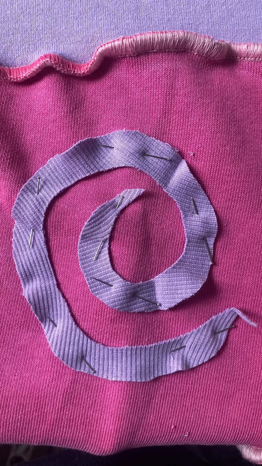 Spirale lilas épinglée sur un sweat fuchsia