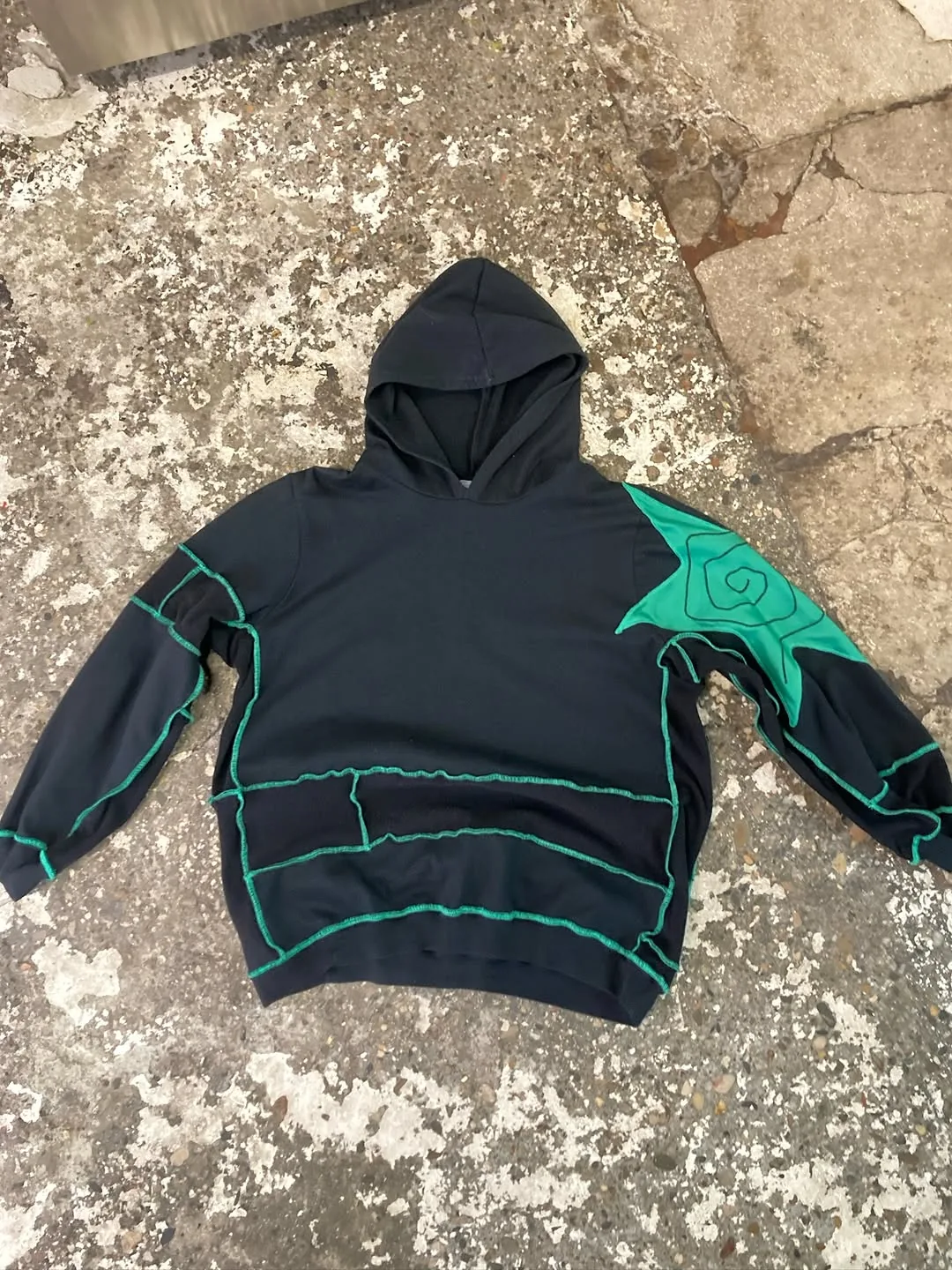 Sweat à capuche noir avec étoile turquoise et surjet vert